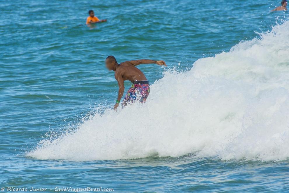 Imagem de um surfista no meio das espumas da onda da Praia da Tiririca.
